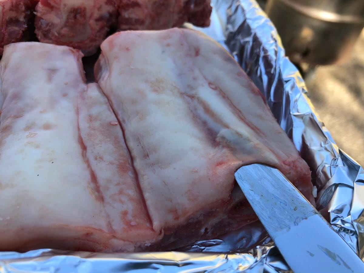 Butter knife pushed under membrane to remove it from the back side of beef finger ribs.