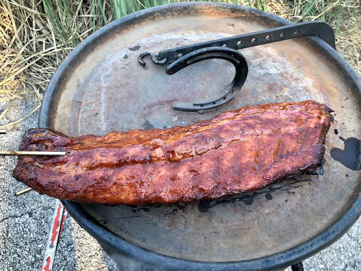 The top lid of the Pit Barrel Cooker gives you a good surface to lay the ribs on so you can apply sauce. I normally only sauce the meat side to keep it simple.