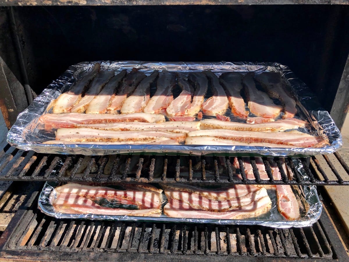Raw bacon layed out on foil lined baking sheets on MAK 2 Star Pellet Grill