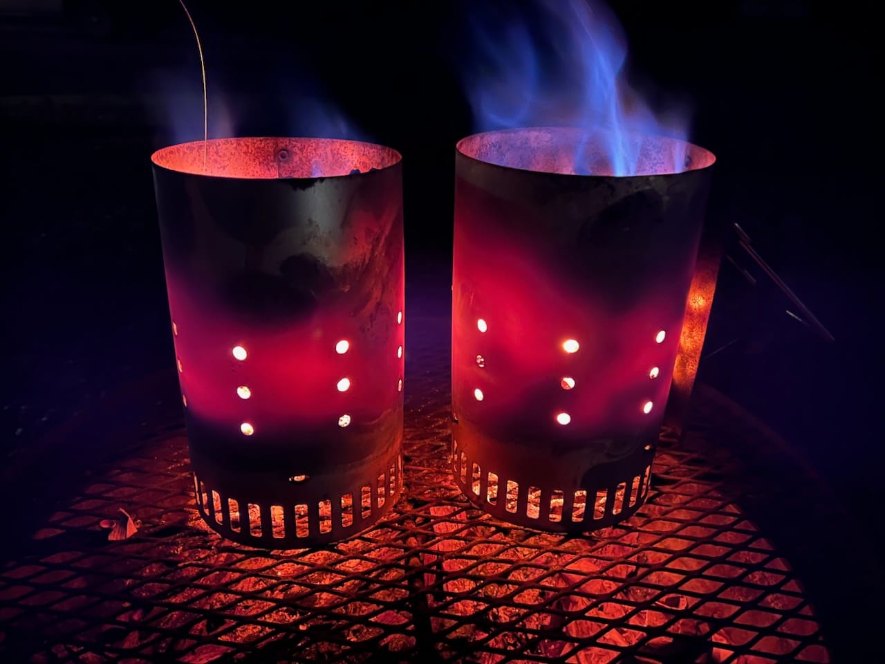 Two Weber charcoal chimneys full of hot coals.