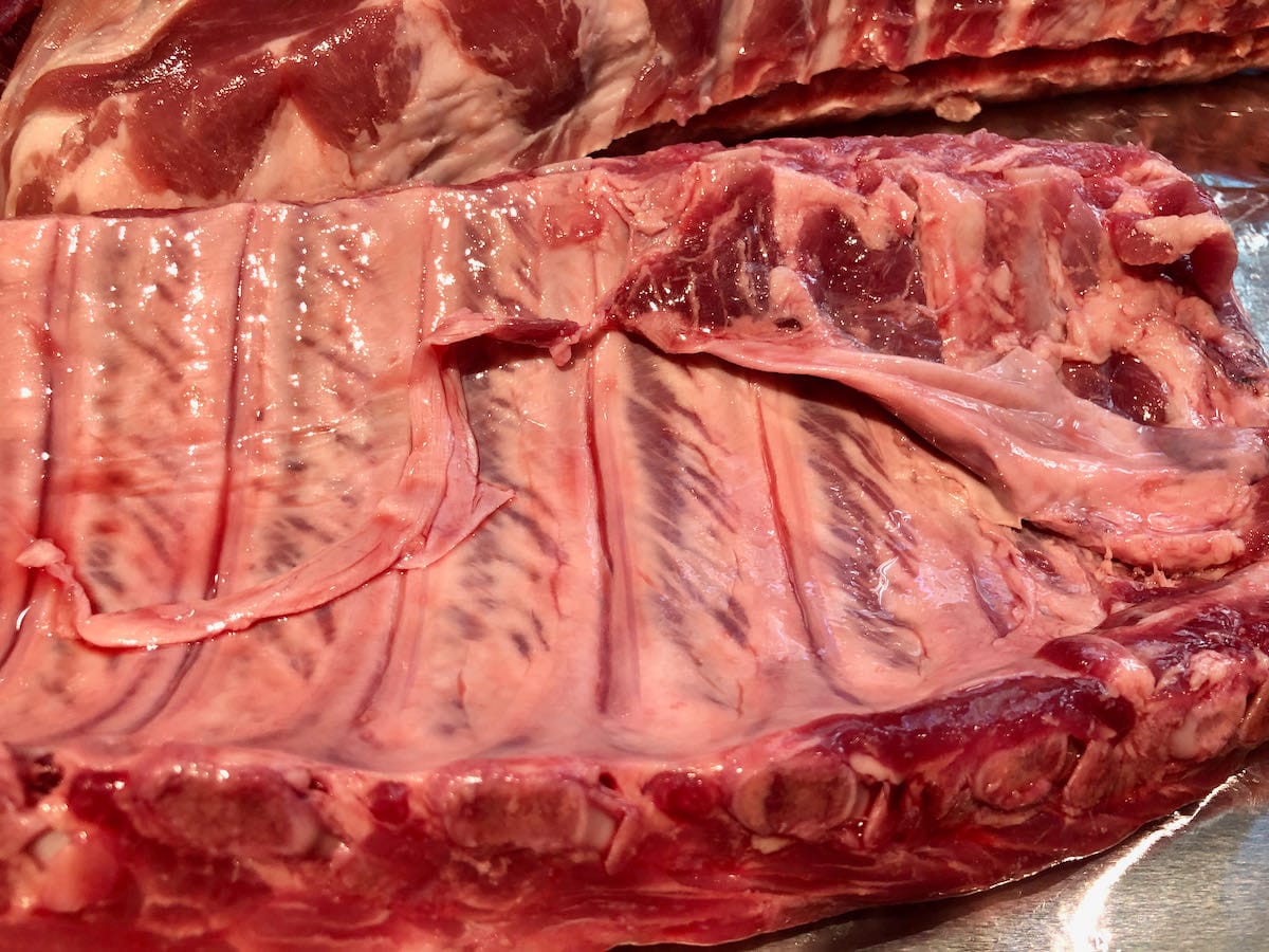 Excess membrane hanging off baby back ribs.