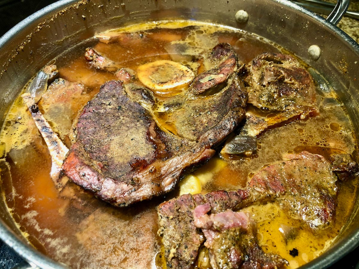 Piedmontese beef cooking in a pan on the stove with onion and garlic.