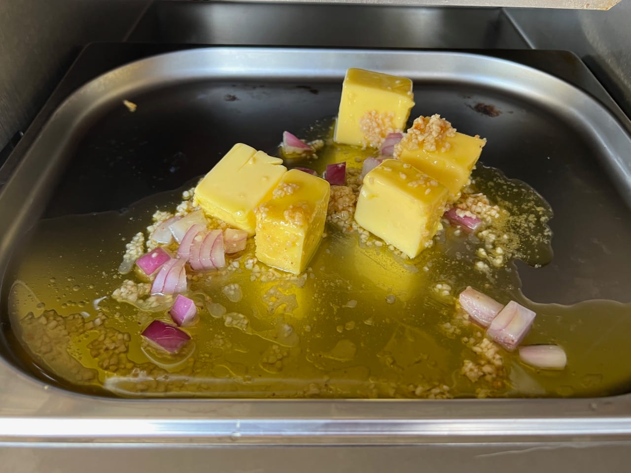 Butter, garlic, onion, and olive oil in Schwank Infrared Grill drip tray.