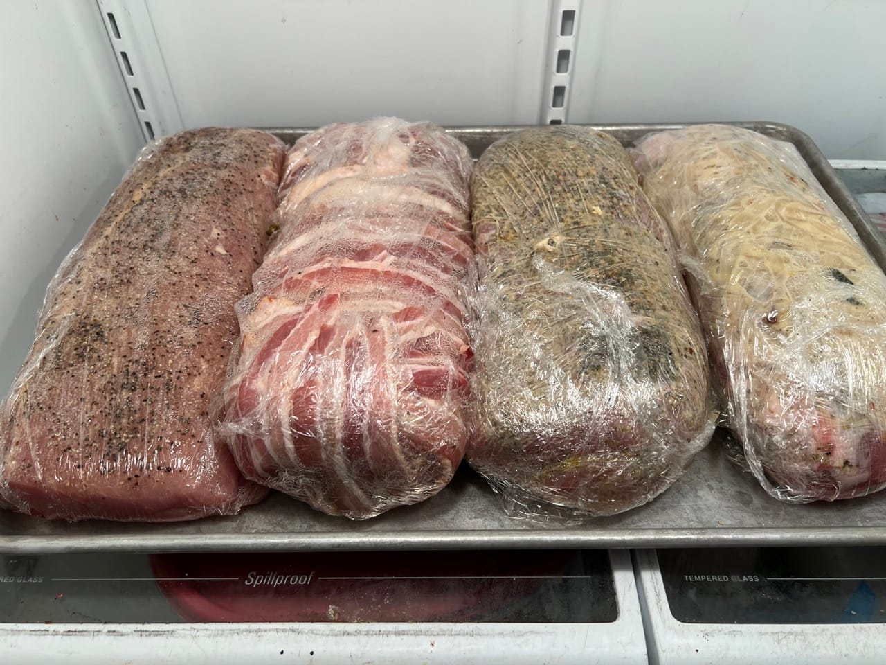 Stuffed pork loins wrapped in plastic wrap.